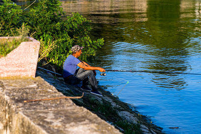 Side view of a man sitting by lake