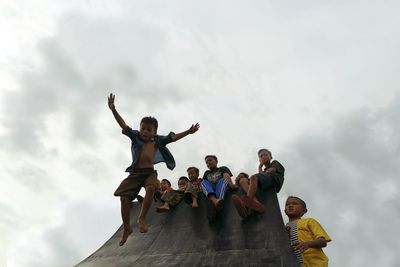 People at low angle view of friends against sky