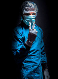 Portrait of young man wearing mask against black background