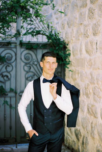 Portrait of young man standing against wall