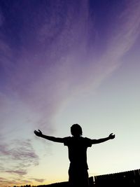 Silhouette of person with arms outstretched against sky