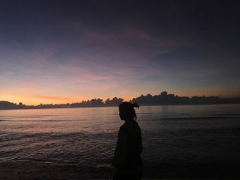 Silhouette man looking at sea against sky during sunset