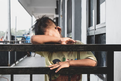 Close-up of sad boy leaning on railing