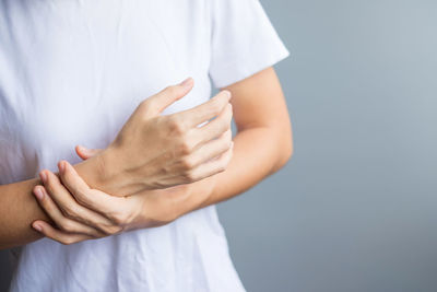 Midsection of woman holding hands against white background