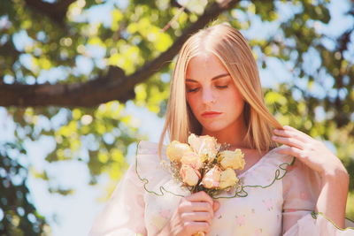 Beautiful woman with roses standing in forest