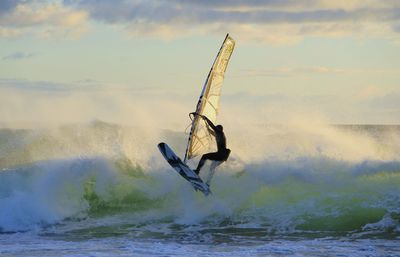 Man surfing in sea against sky