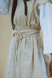 Midsection of woman standing in traditional clothing against brown background