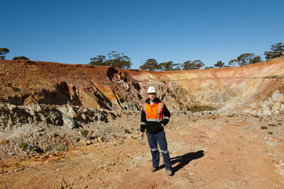 Man standing on rock formation against clear sky