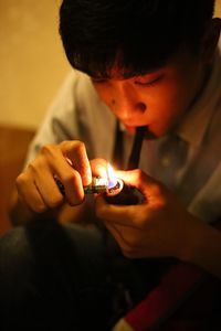 Young man igniting smoking pipe