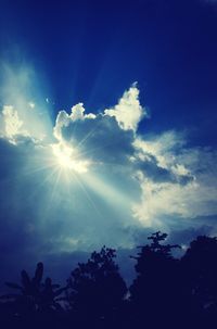 Low angle view of sun shining through clouds