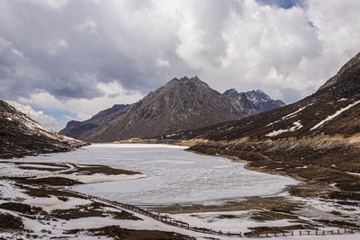 Frozen lake with mountain valley background in winter at day from flat angle