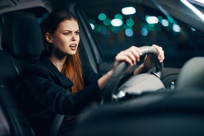 Angry young woman driving car at night