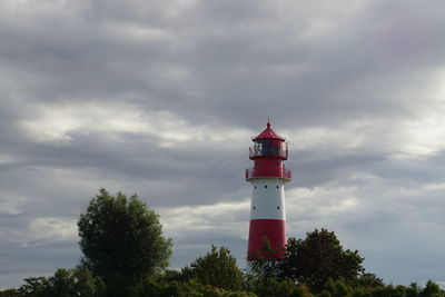 Lighthouse by building against sky