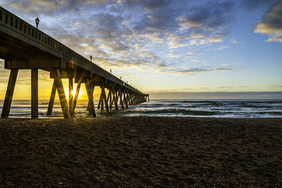 Pier over sea against sky during sunset