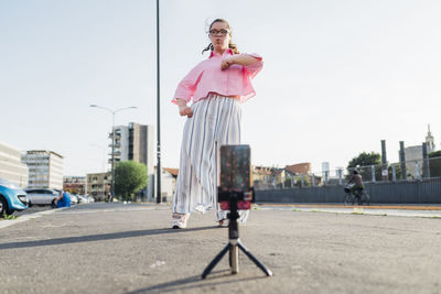 Teenage girl with down syndrome recording dancing video on mobile phone in city