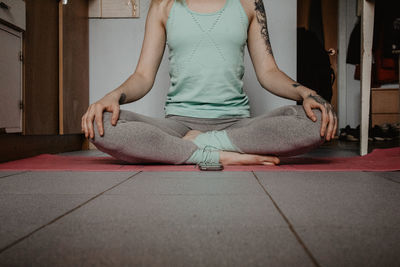 Low section of woman meditating while sitting at home