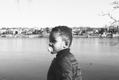 Portrait of boy standing in lake against sky