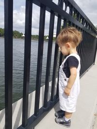 Boy standing by railing in water