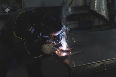 Young welder working with welding torch at workshop