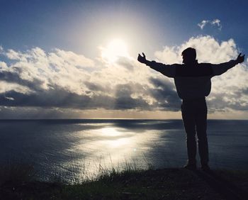 Silhouette of people standing on beach at sunset