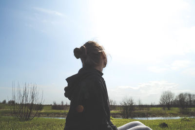 Rear view of woman standing on field against sky