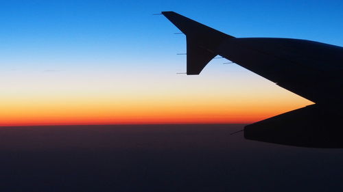 Silhouette of airplane wing against clear sky