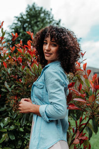 Portrait of smiling young woman standing against plants