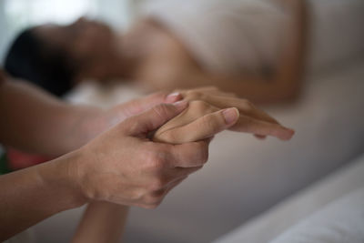 Midsection of therapist massaging young woman hand in spa