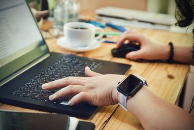 Midsection of woman using laptop on table