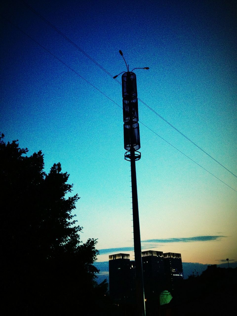 low angle view, building exterior, communication, built structure, guidance, architecture, silhouette, clear sky, tower, tree, sky, dusk, direction, technology, fuel and power generation, directional sign, tall - high, outdoors, road sign, no people