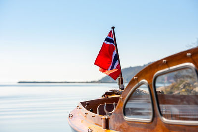 Red flag on sea against clear sky