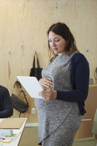 Pregnant professional looking at digital tablet in workplace