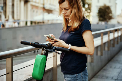 Woman unlock electric scooter for rent with a smartphone application