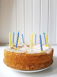 Close-up of birthday cake on table against wall