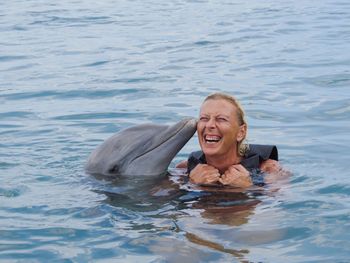 High angle view of dolphin kissing cheerful woman in sea