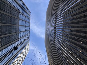 Low angle view of skyscrapers against cloudy sky