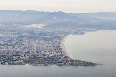 Aerial view of city by sea against sky