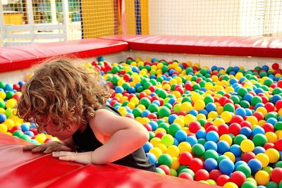 Low angle view of girl sitting on multi colored playing