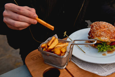 Cropped image of person eating french fries at restaurant