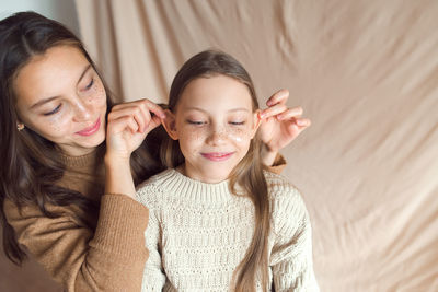 Sisters having fun on beige color textile background