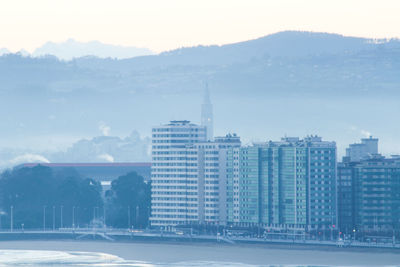 Buildings in city against cloudy sky