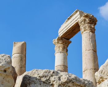 Low angle view of ruins at amman citadel against blue sky