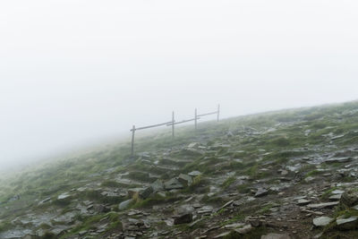 View of railing in field in foggy weather