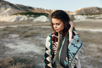 Portrait of young woman standing against mountain