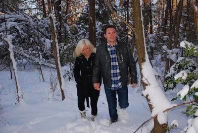 Full length portrait of smiling young woman standing in snow