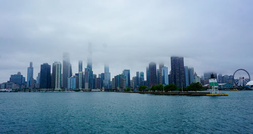 View of city buildings by sea against sky