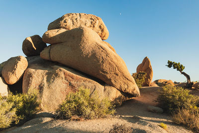 Rock formations on landscape against clear blue sky