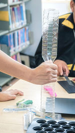 Midsection of person holding bottles on table