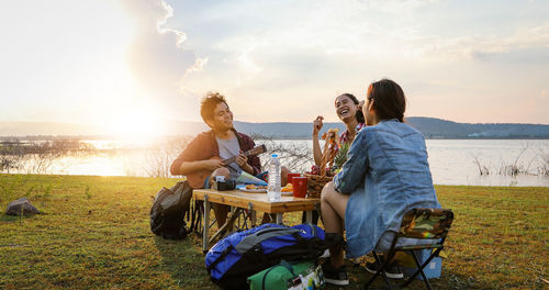 Young couple sitting on land against sky during sunset