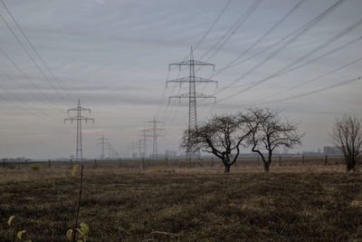 Electricity pylon on field against sky